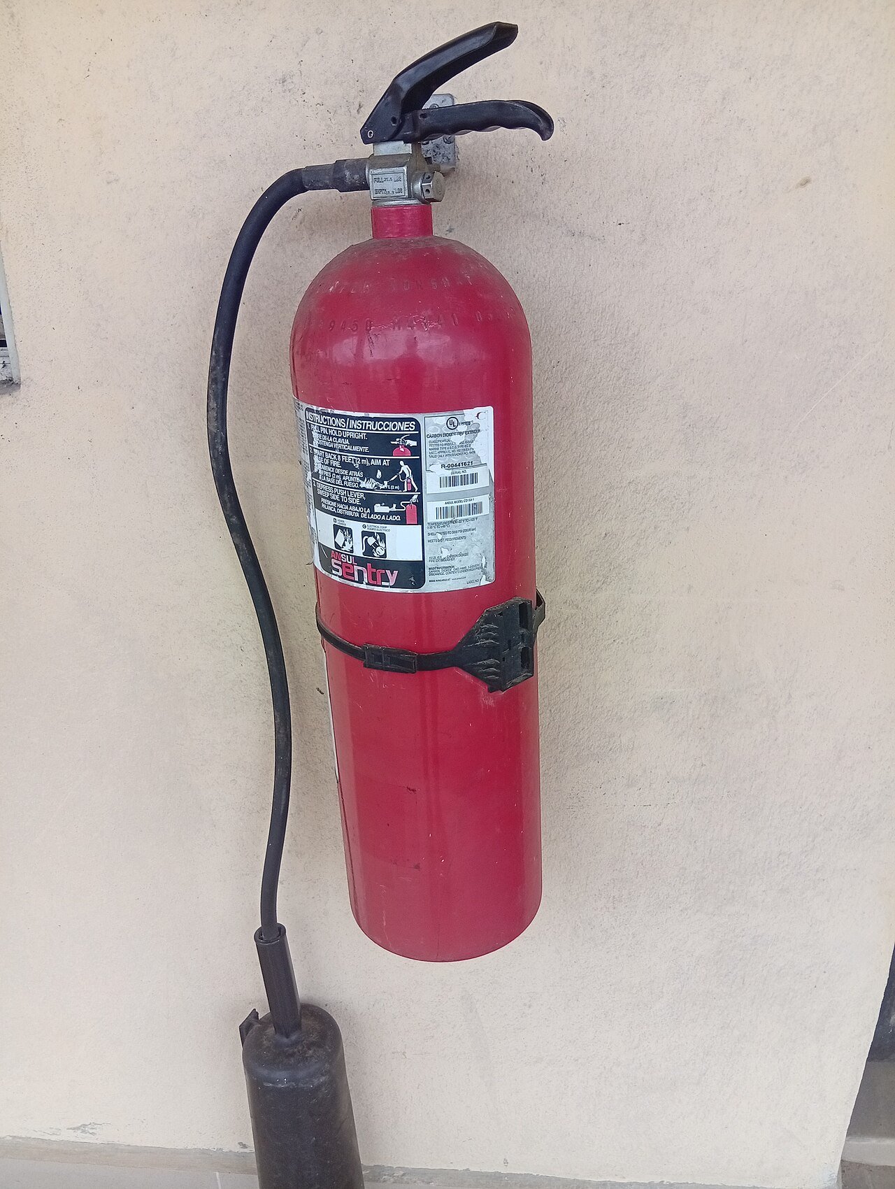 A wall-mounted fire extinguisher with inspection instructions